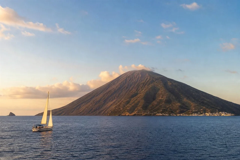Sailboat passing Stromboli in the Aeolian Islands Italy at sunset