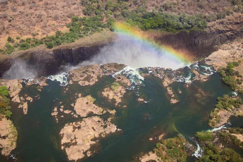 Aerial view of Victoria Falls on the Zambezi River with a rainbow arching over the gorge