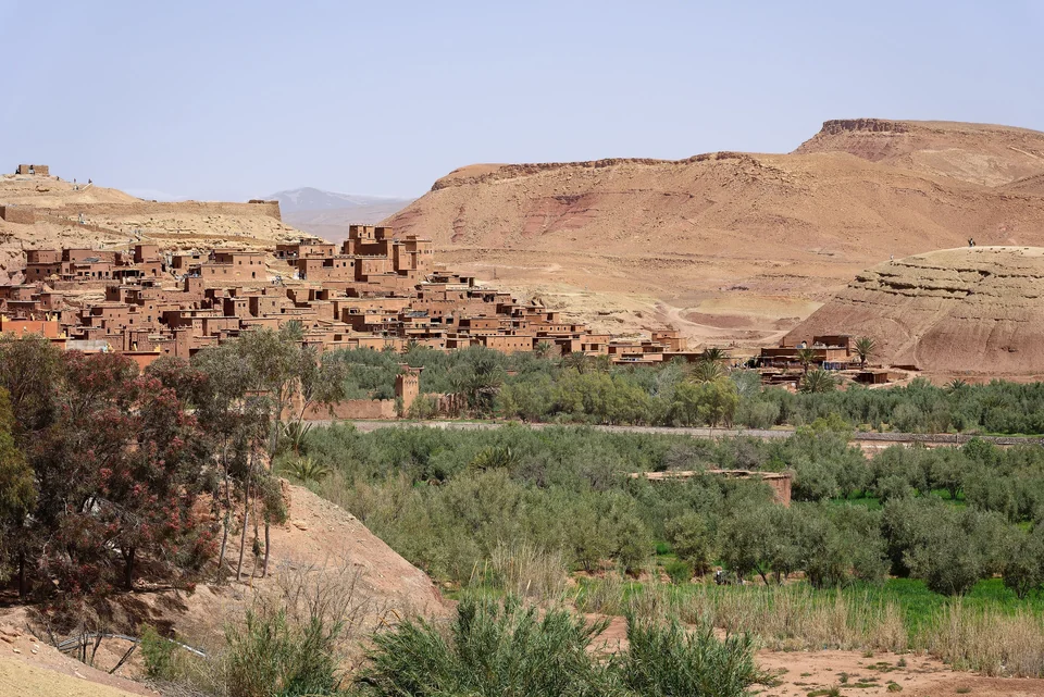 El ksar de Aït Benhaddou en Marruecos, casas de adobe rojo sobre un verde valle fluvial con olivos