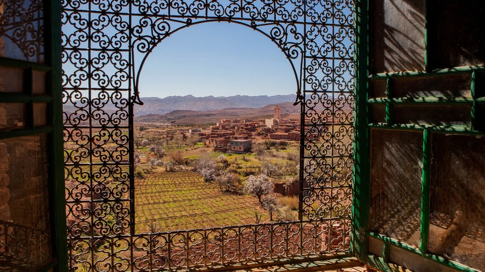 Wrought-iron window frame in the Telouet kasbah looking out over the village, farmland and mountains