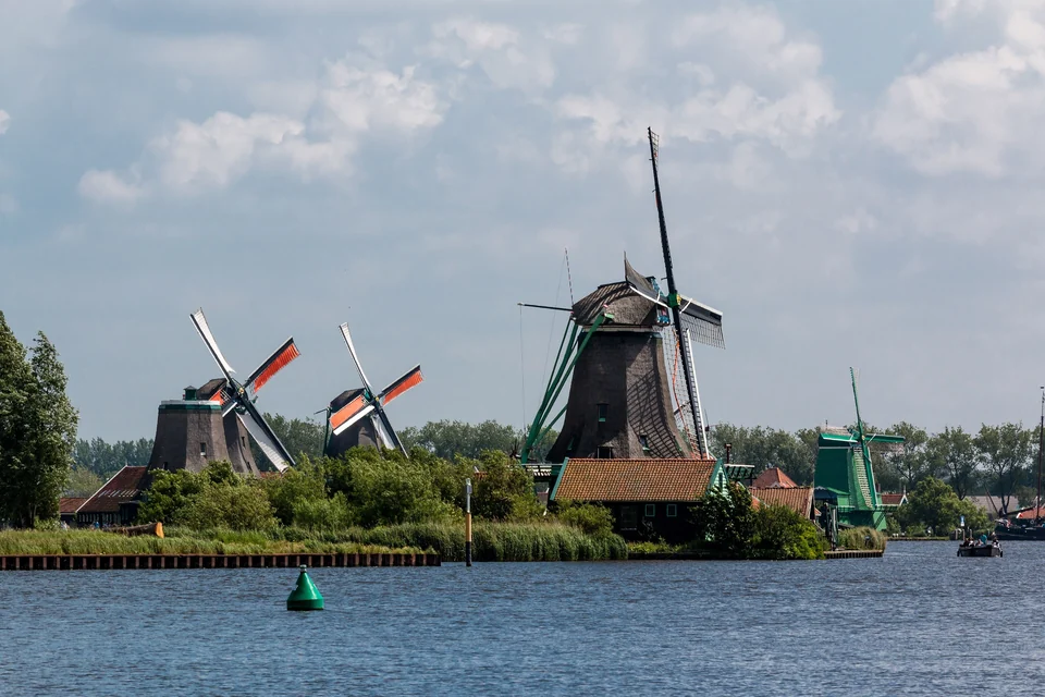 Eine Reihe traditioneller holländischer Windmühlen an einer Gracht in Zaanse Schans bei Amsterdam