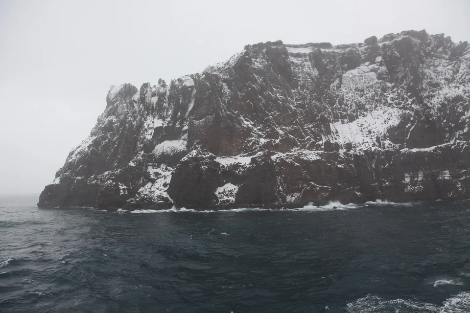 Narrow entrance of Neptune’s Bellows between dark volcanic cliffs leading into Port Foster, Deception Island