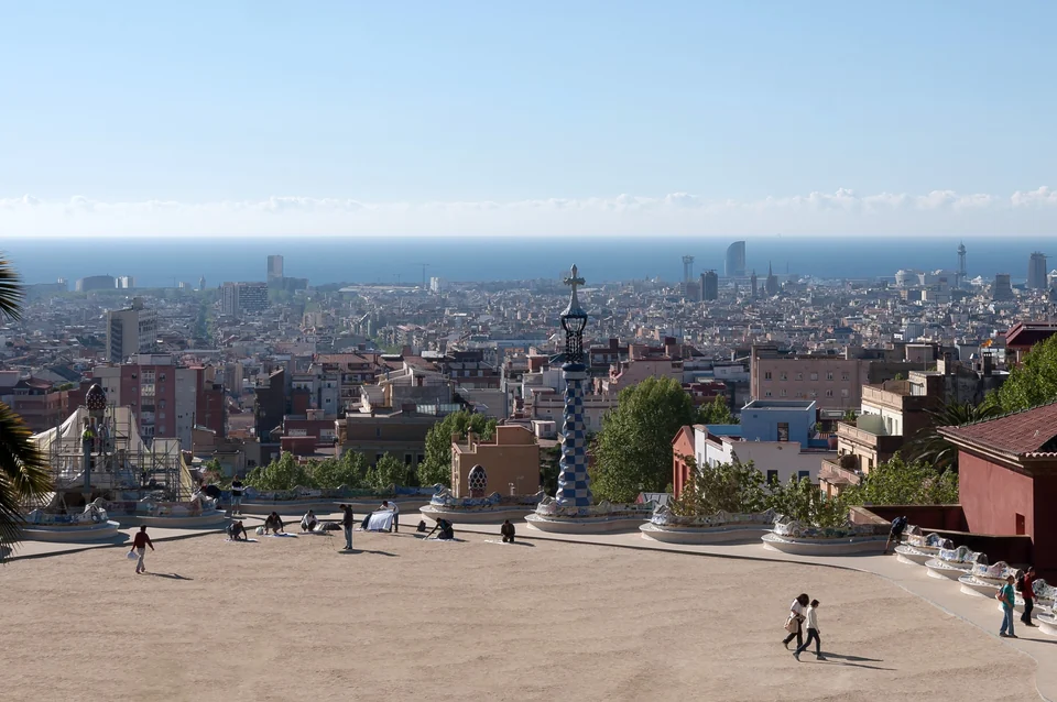 Bancos de mosaico con forma de ola en la terraza principal del Park Güell, con Barcelona al fondo