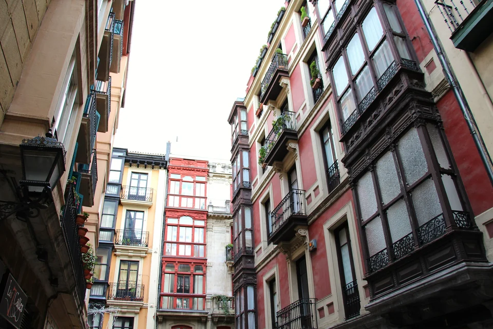Tall painted houses with glazed wooden balconies on Kapelagile Kalea in Bilbao's Casco Viejo