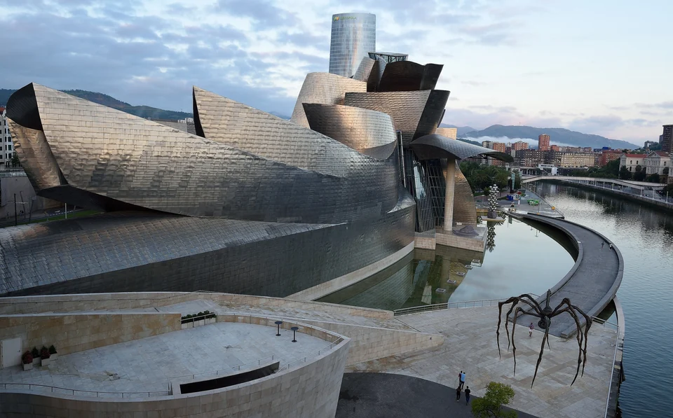 Guggenheim Museum Bilbao's titanium curves beside the Nervión River, with Louise Bourgeois's spider sculpture Maman