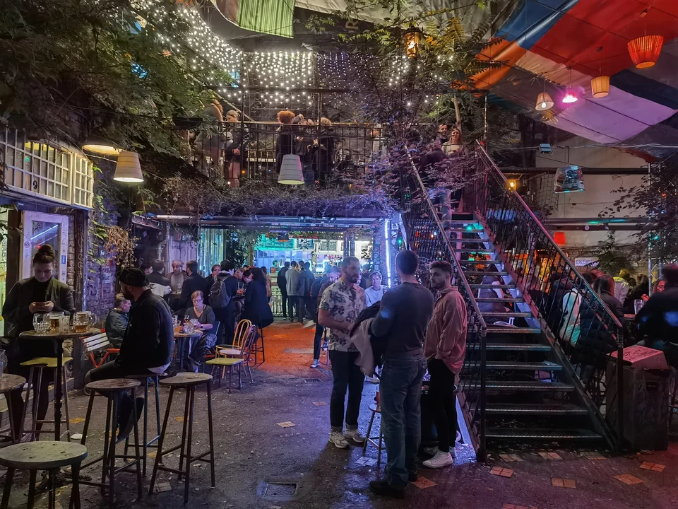 Voller Innenhof des Szimpla Kert, einer Ruinenbar im jüdischen Viertel von Budapest, gefüllt mit zusammengewürfelten Möbeln und Gästen