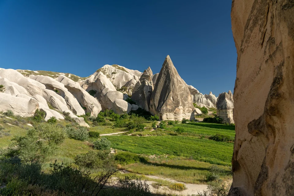 Walkers on a trail through the red rock badlands and fairy chimneys of Red Valley near Göreme