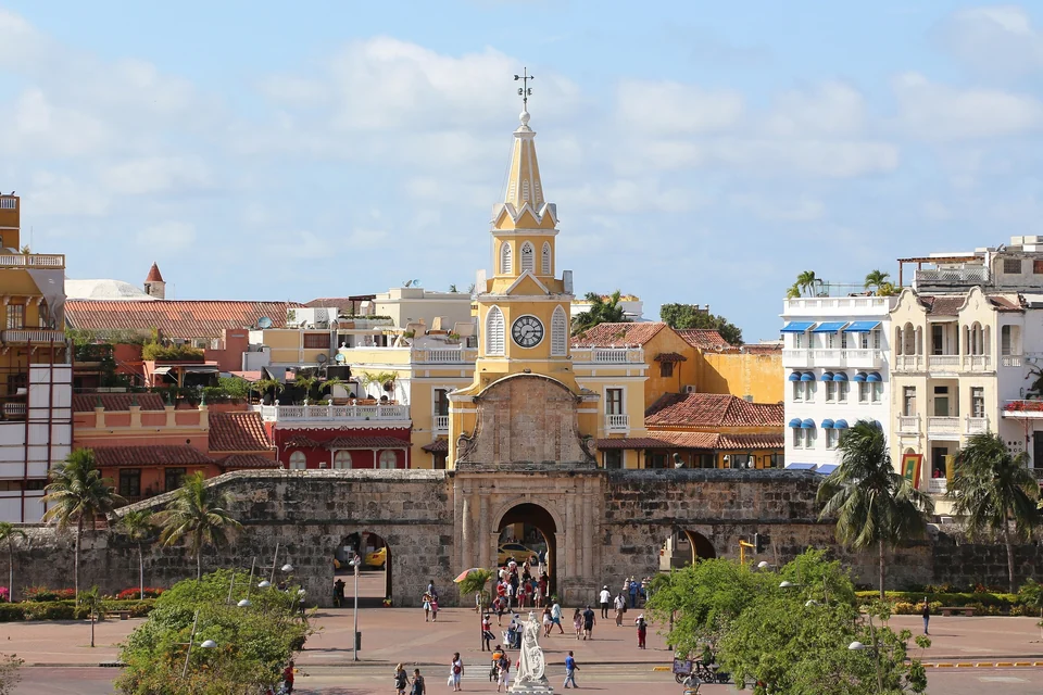 The yellow Clock Tower gate set in the stone walls of Cartagena's old town, with colonial buildings behind it