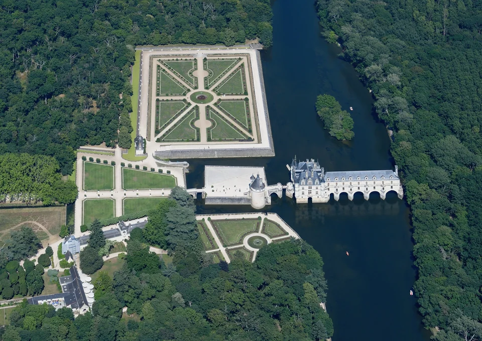Aerial view of the Château de Chenonceau spanning the River Cher with its formal gardens and surrounding forest
