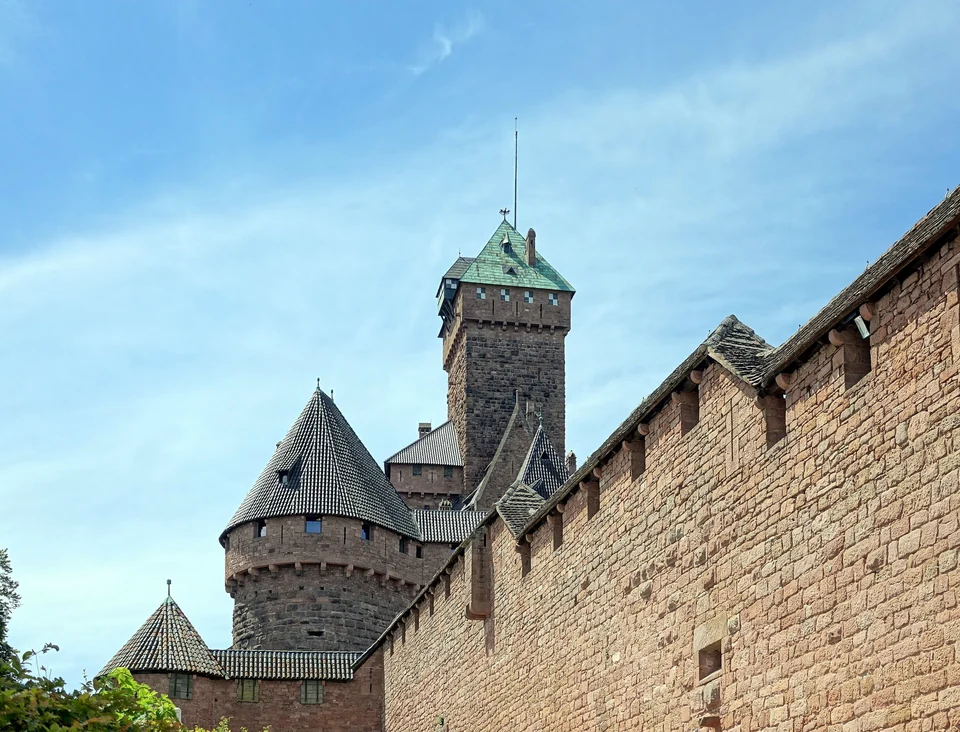 Red sandstone walls and square keep of the Château du Haut-Koenigsbourg in Alsace against a blue sky