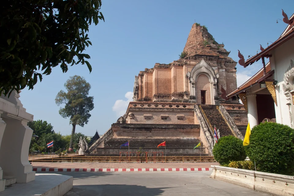 The ruined brick chedi of Wat Chedi Luang in Chiang Mai's Old City, with naga stairways and prayer flags under a blue sky