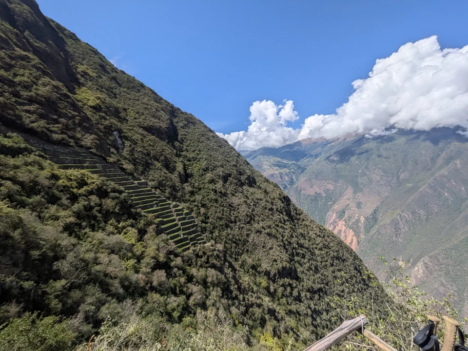 Wide view of the stepped llama terraces at Choquequirao with the mountain ridge behind