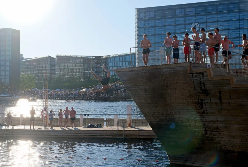 Swimmers lining up to jump from a platform into the harbor at the Islands Brygge harbor bath in Copenhagen