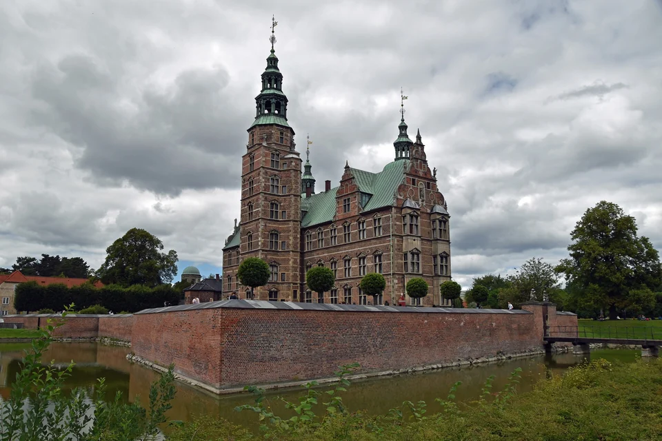 Red-brick Rosenborg Castle with green copper spires behind its moat and lawns in central Copenhagen
