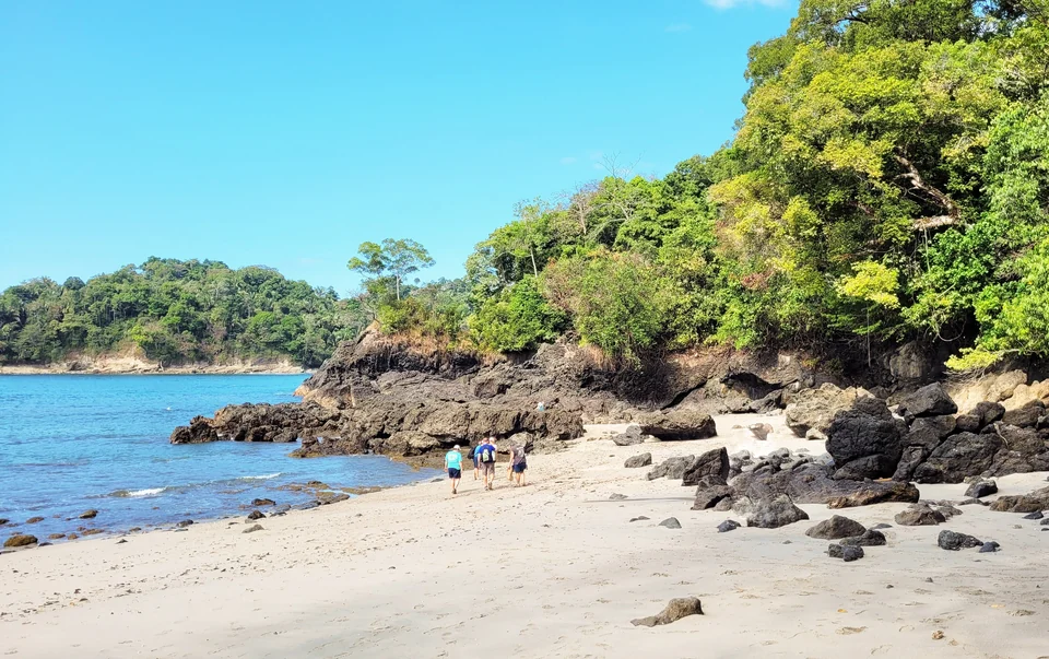Curved white-sand beach backed by rainforest inside Manuel Antonio National Park on Costa Rica's Pacific coast