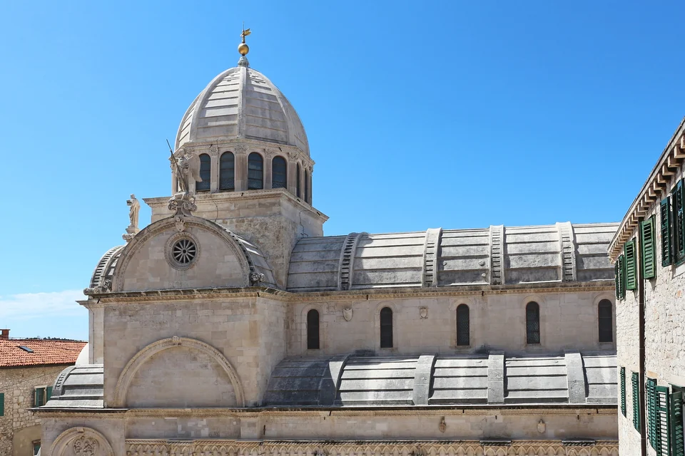 Stone dome and barrel-vaulted stone roof of the Cathedral of St James in Šibenik under a clear blue sky