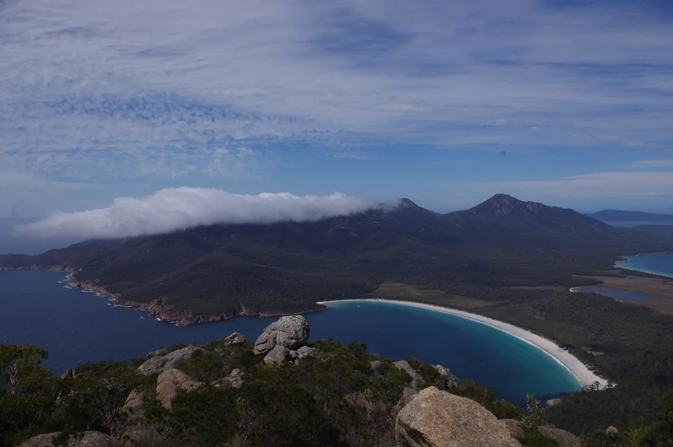 Curved white beach of Wineglass Bay between forested mountains on the Freycinet Peninsula, Tasmania