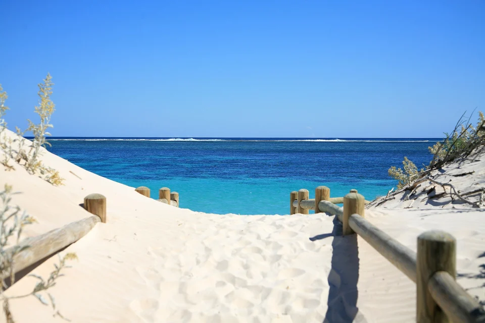 White sand path and wooden railing leading to the turquoise water of Ningaloo Reef, Western Australia