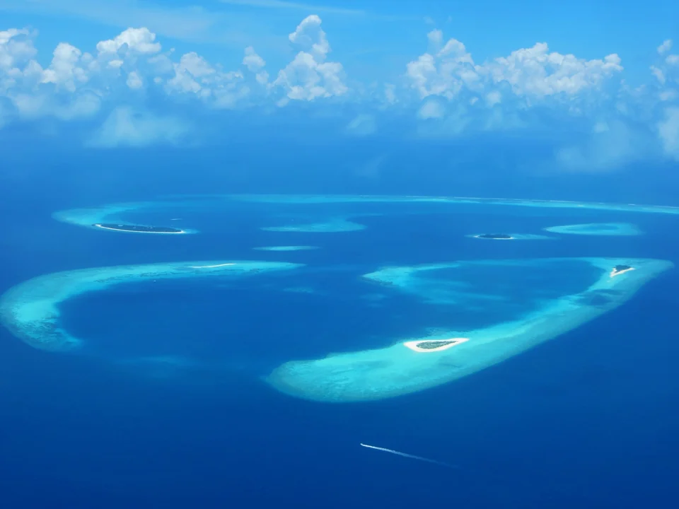 Aerial view of ring-shaped coral reefs and small islands in turquoise water in Baa Atoll, Maldives