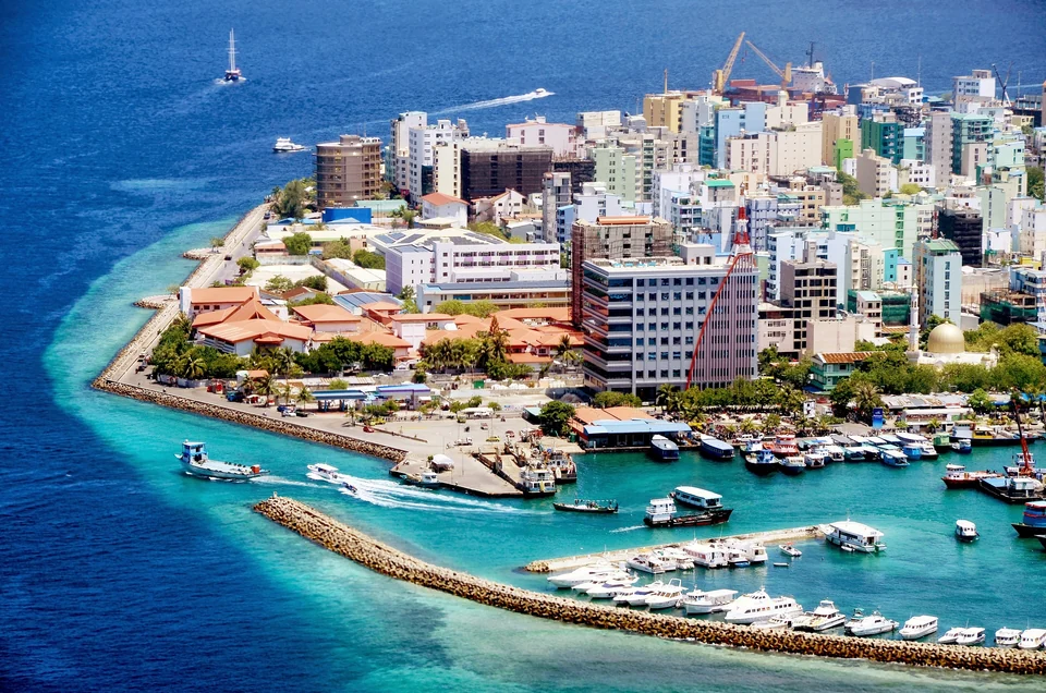 Aerial view of Malé, capital of the Maldives, with dense buildings covering the whole island and boats in the harbor