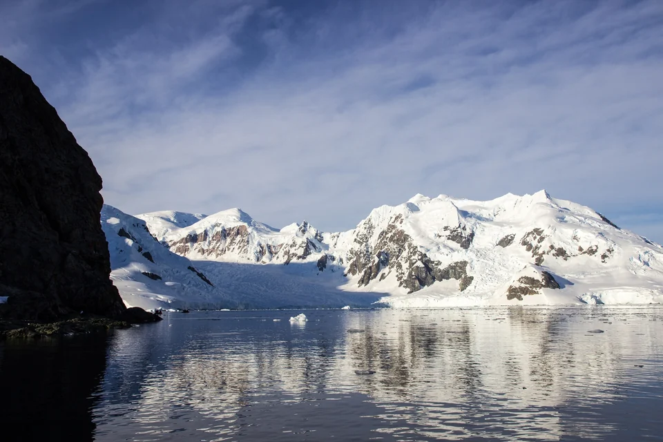 Snow-covered mountains and glaciers reflected in calm water at Paradise Bay on the Antarctic Peninsula
