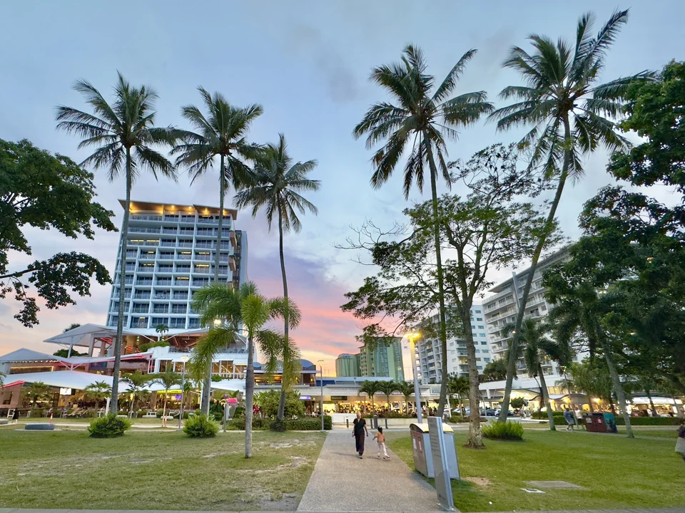 Palm trees and lawns along the Cairns Esplanade at twilight with hotels behind, Tropical North Queensland