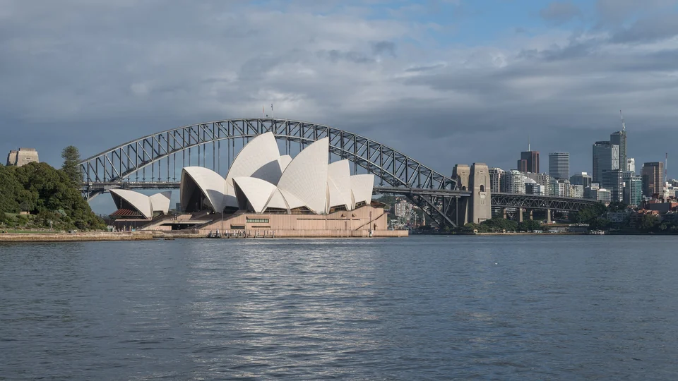 Sydney Opera House sails in front of the Sydney Harbour Bridge and city skyline across the harbor