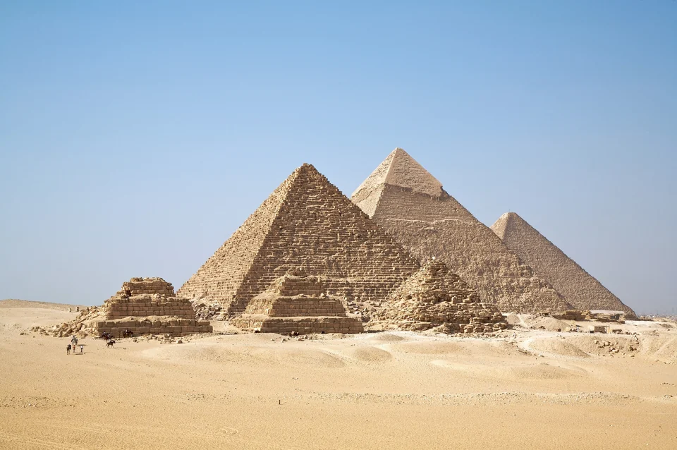 The pyramids of Giza, including the smaller queens’ pyramids, standing on the desert plateau under a pale sky