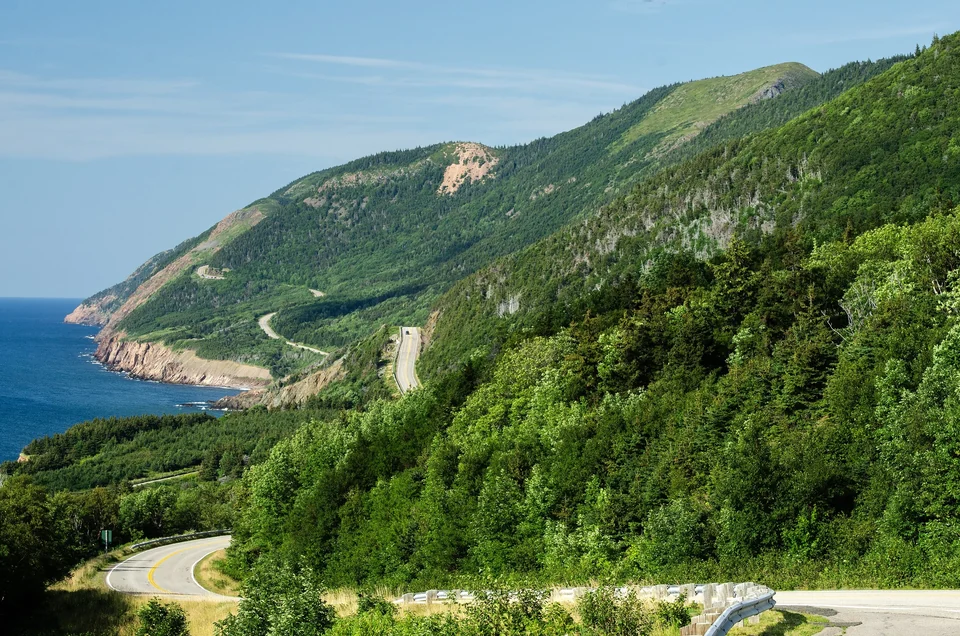 Cabot Trail road winding along green coastal hills above the sea in Cape Breton Highlands National Park