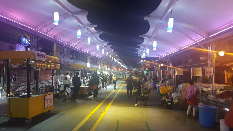 Illuminated covered street with food carts at Seomun Night Market in Daegu at dusk