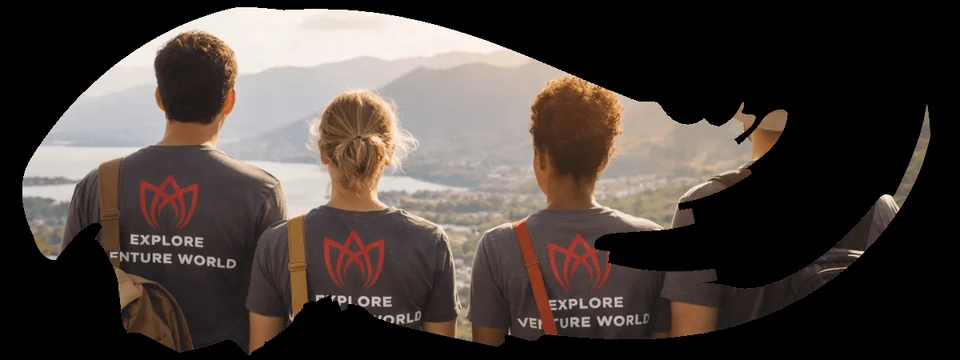 Four travelers in Explore Venture World T-shirts looking out over a lake and mountains