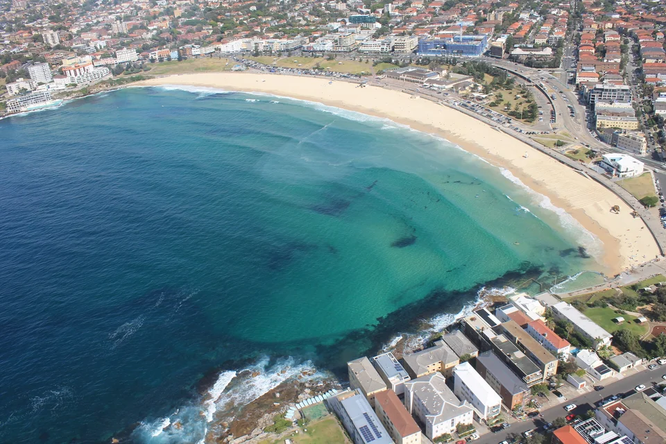 Aerial view of the curved sandy shore and turquoise water of Bondi Beach in Sydney's eastern suburbs