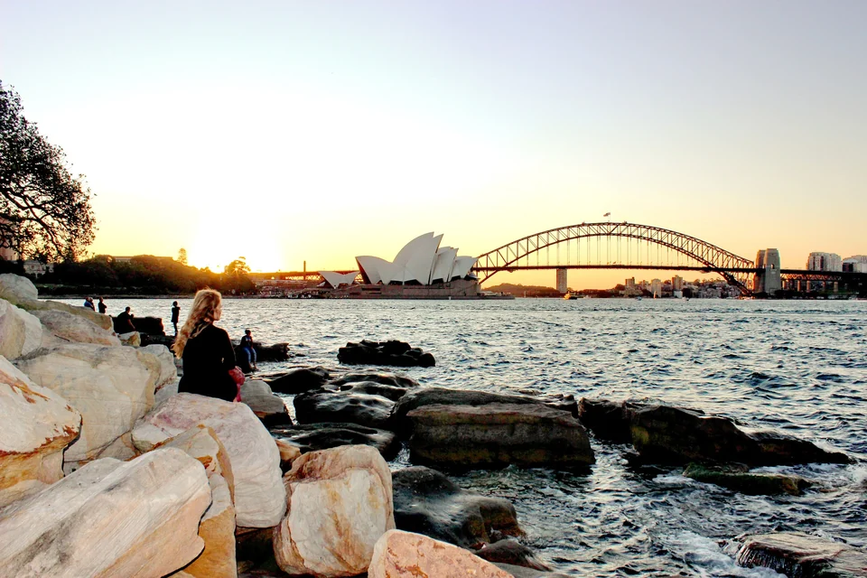 Sydney Opera House and Harbour Bridge silhouetted at sunset, seen from the sandstone rocks at Mrs Macquarie's Chair