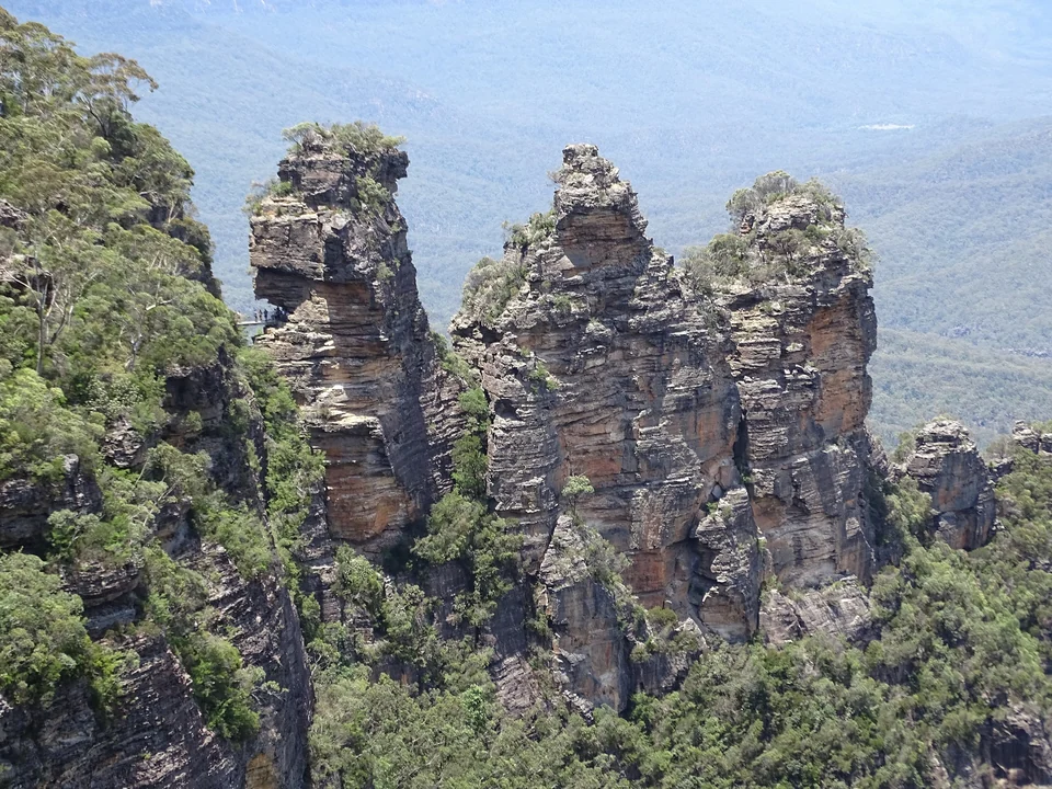 The Three Sisters sandstone rock formation rising above forested valleys in the Blue Mountains, seen from Echo Point
