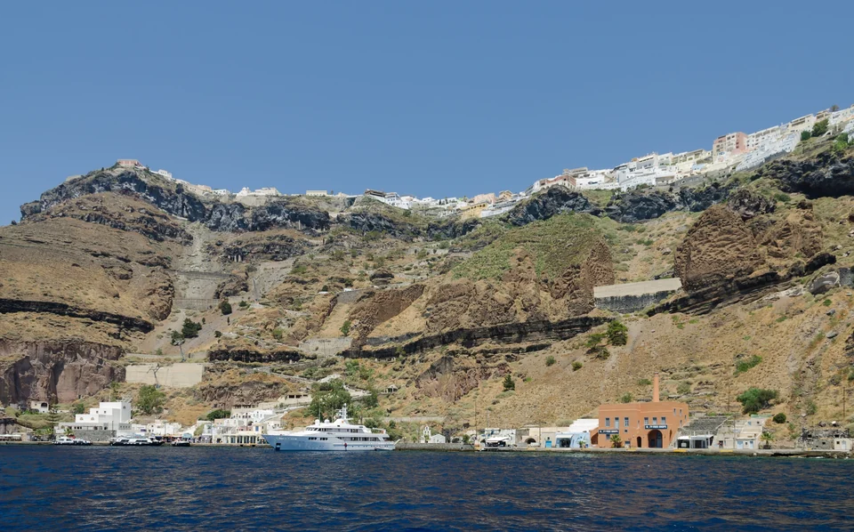 Fira’s white houses along the top of the caldera cliffs above the old port of Santorini, seen from the sea