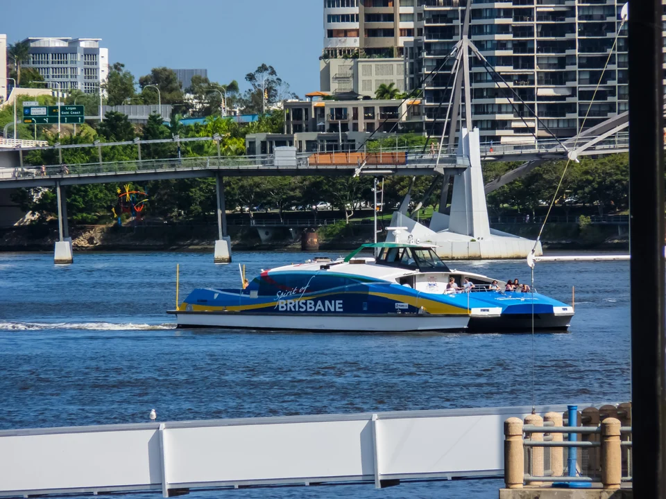 Blue and white CityCat ferry cruising the Brisbane River past the Kurilpa pedestrian bridge