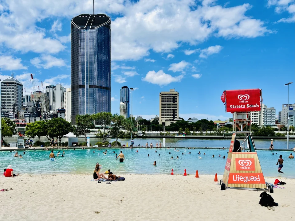 Swimmers in the lagoon at Streets Beach, South Bank Parklands, with Brisbane city towers across the river