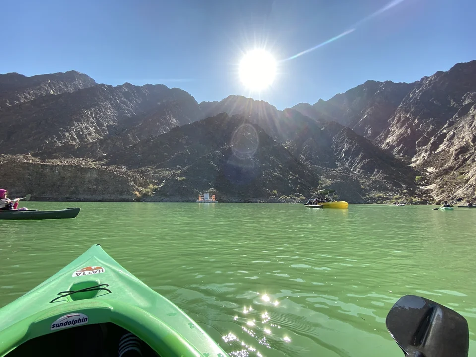 Kayakers paddling on the Hatta Dam reservoir with hills behind, Hatta, United Arab Emirates