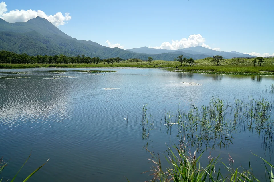 Calm Lake Ichiko reflecting forest and distant mountains in the Shiretoko Five Lakes area