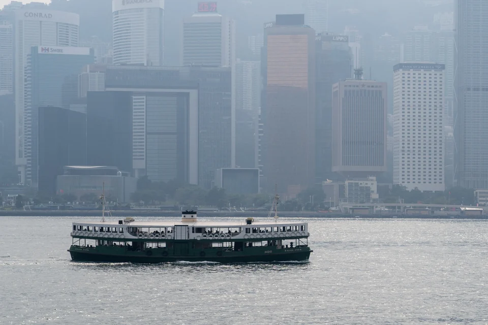 A green-and-white Star Ferry crossing Victoria Harbour with the Hong Kong Island skyline behind