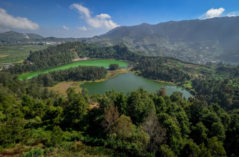 Bright green Telaga Warna and darker Telaga Pengilon lakes among forest and terraced fields on the Dieng Plateau