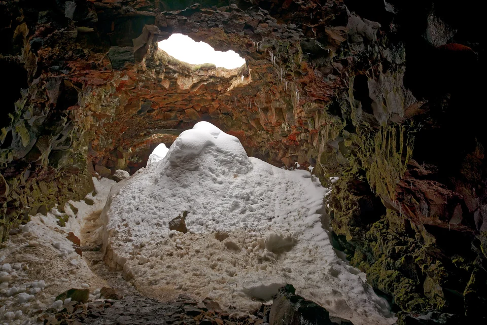 Wide lava tube interior of Raufarhólshellir cave in Iceland with colorful rock walls lit by artificial lights