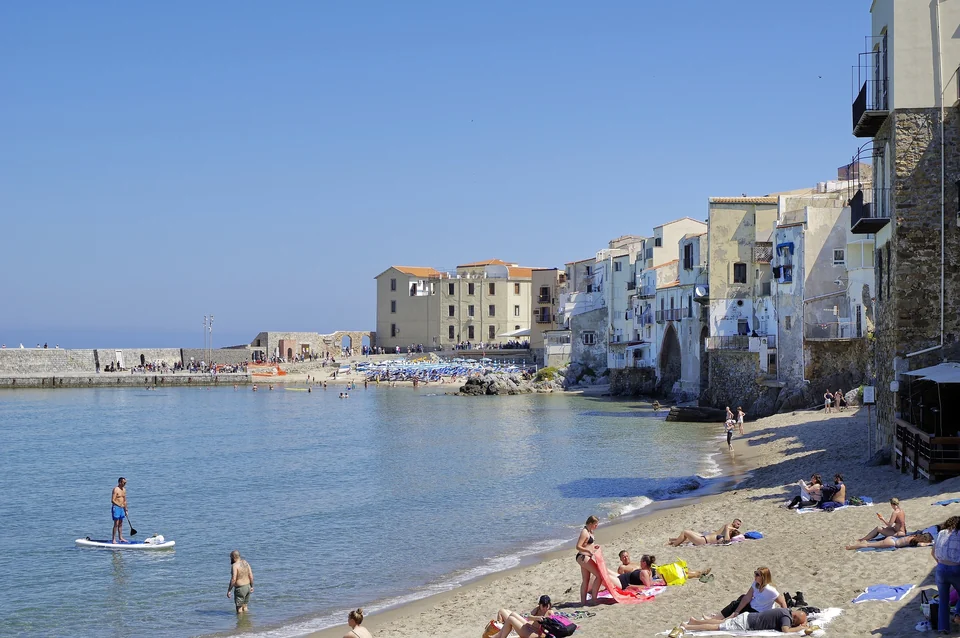 Sandstrand in Cefalù auf Sizilien mit den Häusern der Altstadt und dem Hafen dahinter