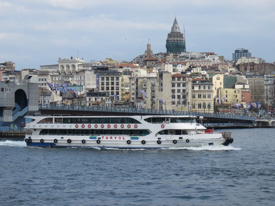 Un bateau de passagers traverse la Corne d'Or devant le pont de Galata, avec la tour de Galata sur la colline au-dessus