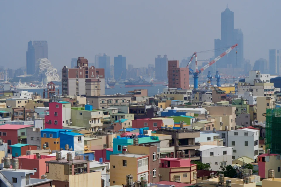 Colorful rooftops on Cijin Island with Kaohsiung harbor cranes, the Music Center and 85 Sky Tower behind