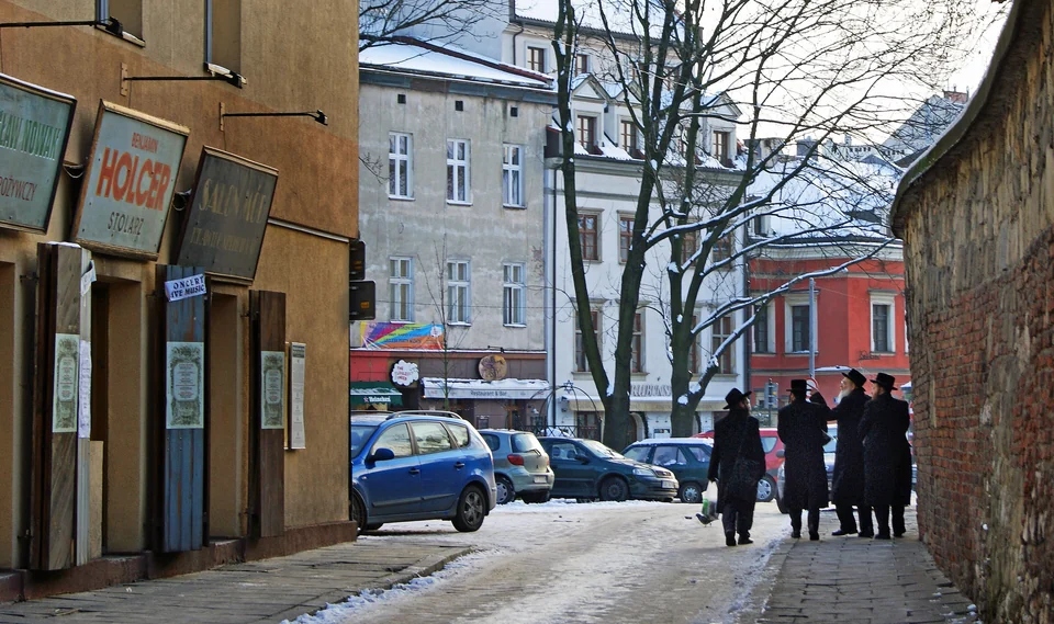 Szeroka Street in Kazimierz, Kraków, after snowfall, with old painted shop signs on a building facade