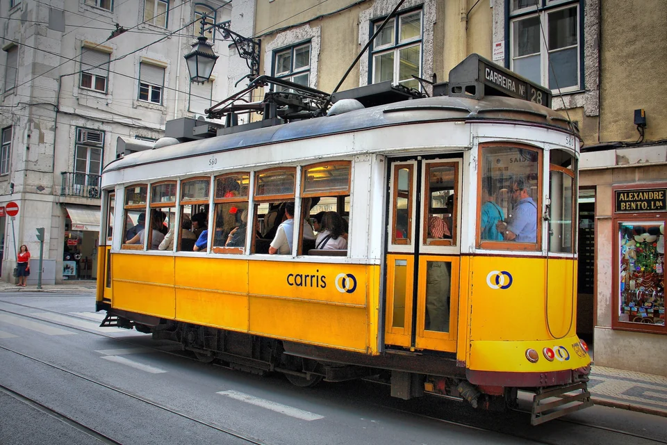 Yellow Carris tram number 28 on a narrow cobbled street in central Lisbon