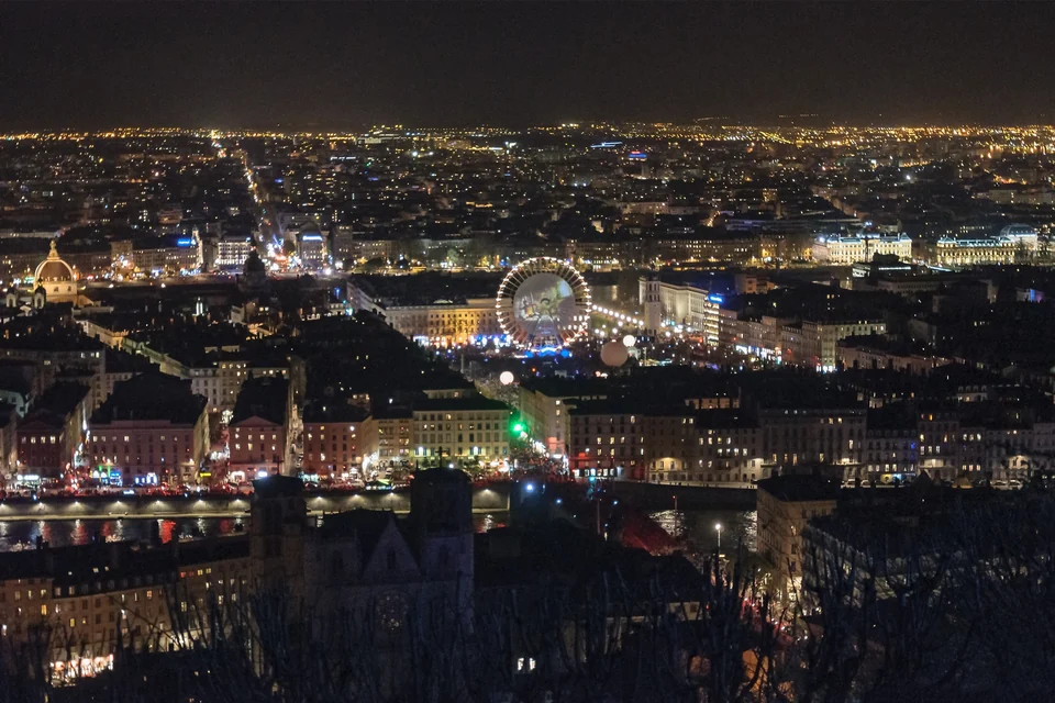 Lyon at night during the Fête des Lumières, with an illuminated Ferris wheel on Place Bellecour seen from Fourvière