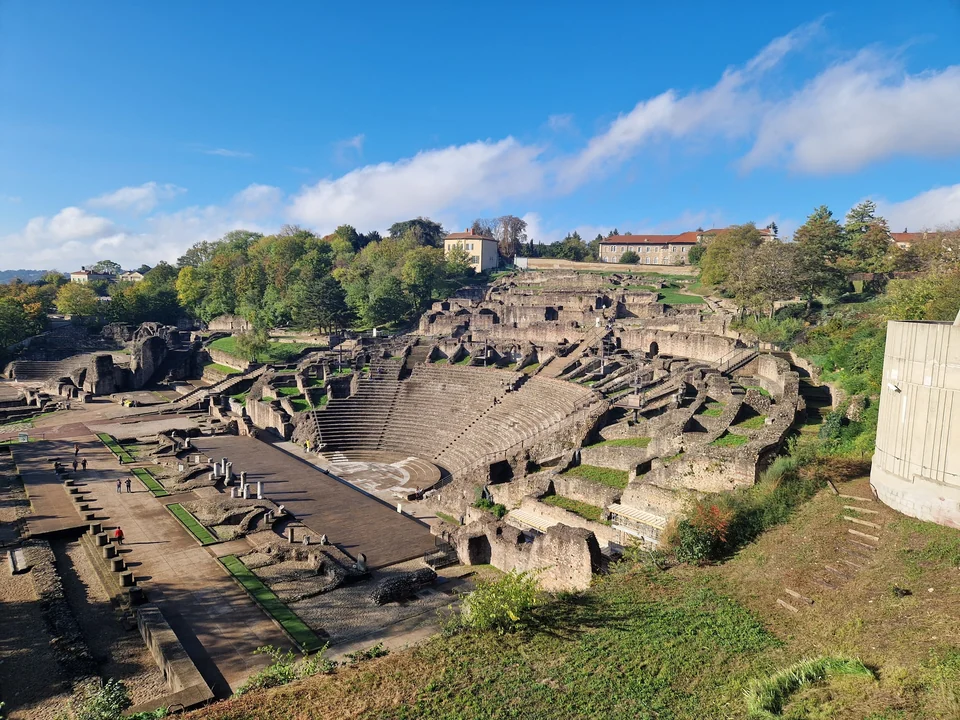 Tiered stone seating and stage of the Roman theater on Fourvière hill in Lyon under a blue sky