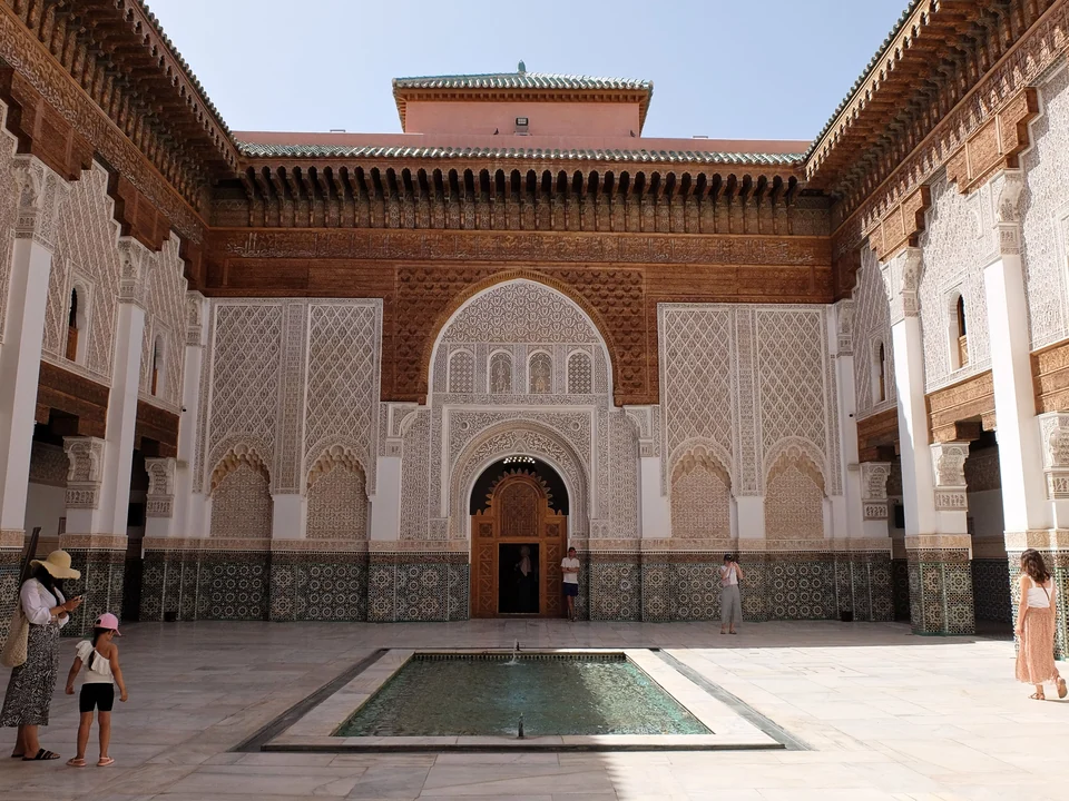 Courtyard of the Ben Youssef Madrasa in Marrakech with a rectangular pool, carved stucco walls and cedar woodwork